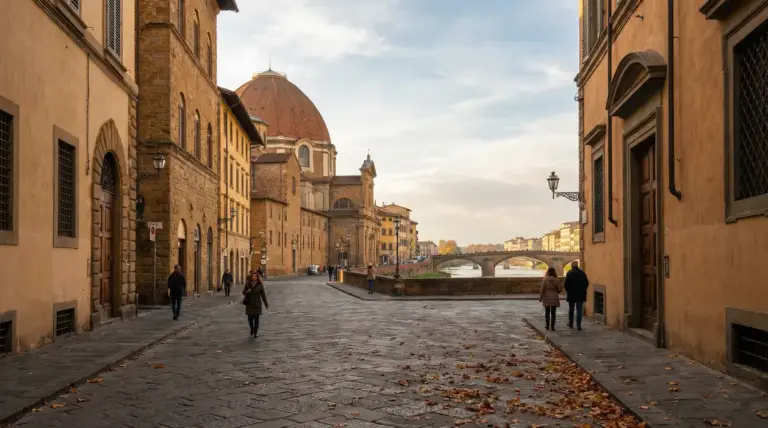 Strada storica di Firenze sul lungarno con cupola, ponte e pochi passanti in una giornata fuori stagione