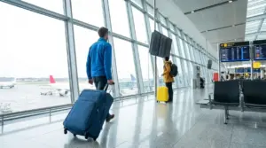 Viaggiatori con valigie nel terminal aeroportuale davanti ai gate di partenza