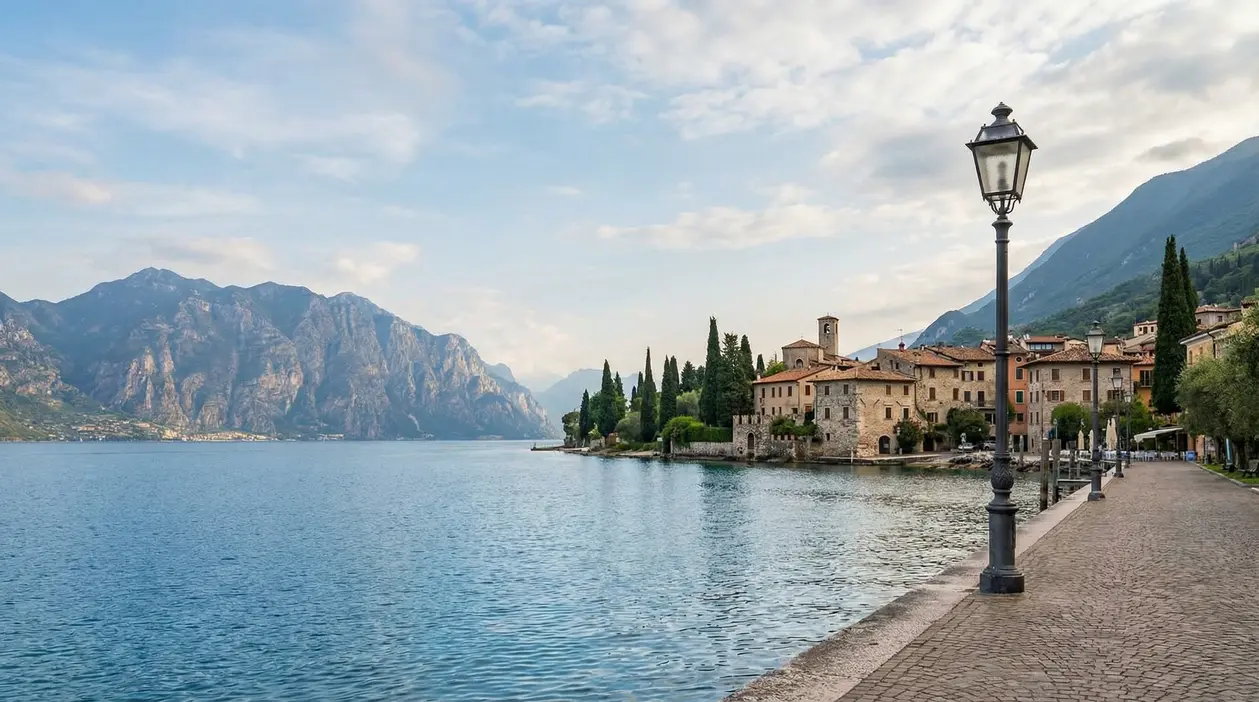 Borgo sul lungolago del Lago di Garda con montagne sullo sfondo e passeggiata tranquilla