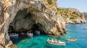 Grande grotta marina in Italia con barche turistiche e kayak su acqua cristallina tra scogliere rocciose