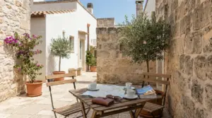 Cortile in pietra di una casa in Puglia con tavolo all'aperto, mappa e tazzine da caffè