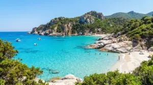 Cala del Sud Italia con acqua cristallina, sabbia chiara, rocce e piccole barche in una baia turchese