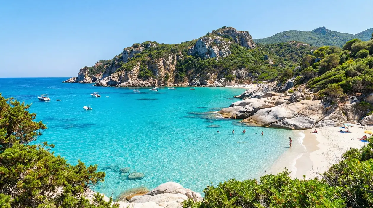Cala del Sud Italia con acqua cristallina, sabbia chiara, rocce e piccole barche in una baia turchese