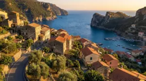 Borgo costiero italiano affacciato su una baia tra scogliere, con case in pietra e piccolo porto al tramonto